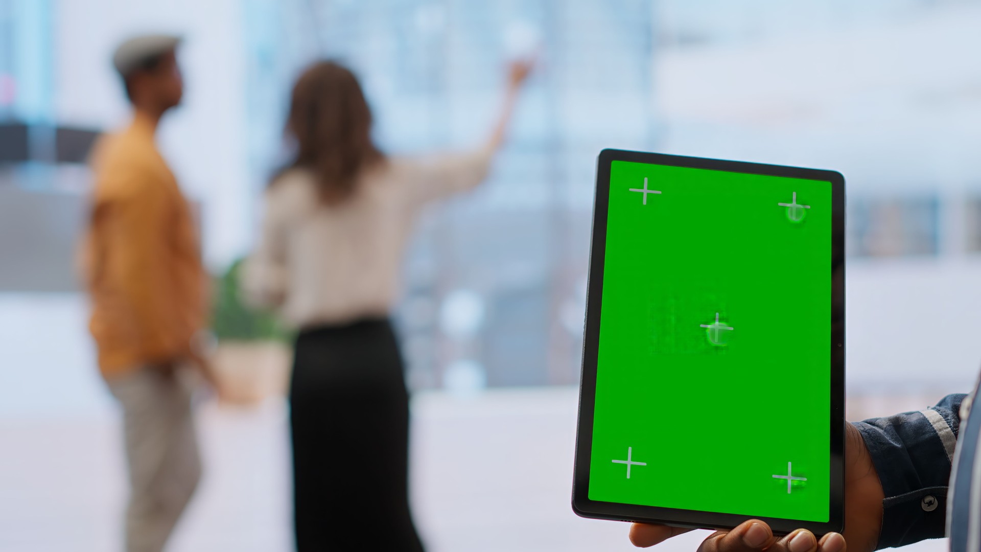 Real estate agents and client examine blueprints next to a green screen